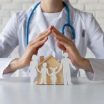 Doctor with stethoscope protecting a paper-family and wooden house, symbolizing family health insurance/care